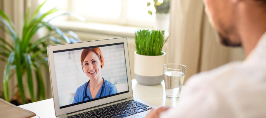 Mature man having video call with doctor on laptop at home, online consultation concept.